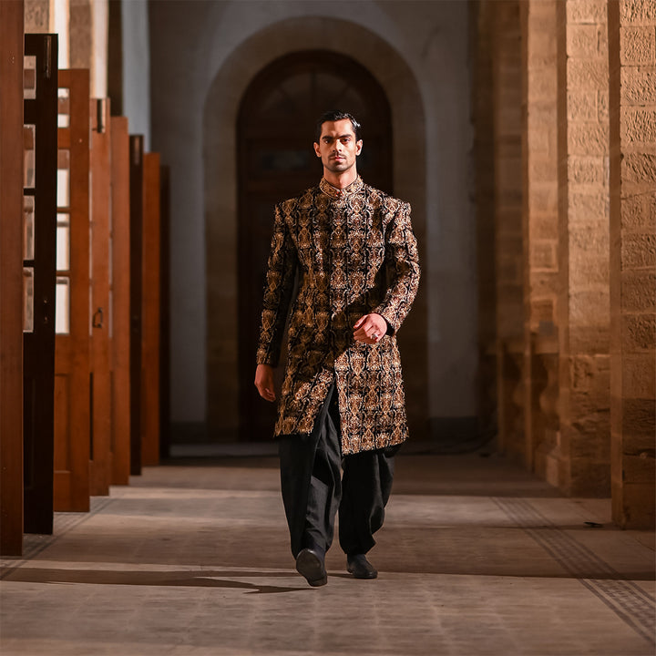 Black velvet sherwani with zari embroidery, paired with black dhoti shalwar.